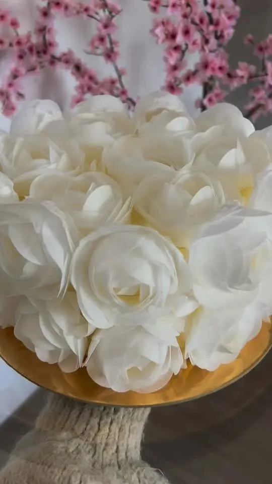 Torte, pārklāta ar baltām rozēm, uz zeltīta paliktņa