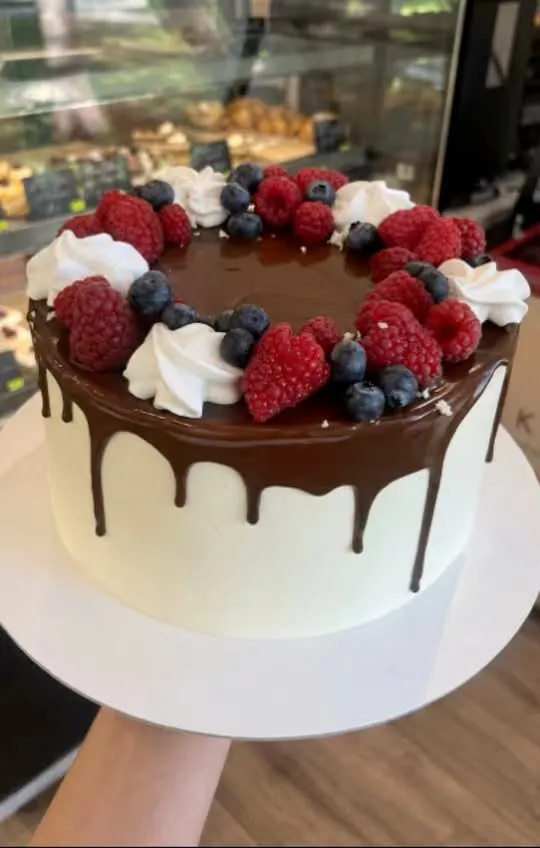 Balta torte ar šokolādes glazūru, avenēm, mellenēm un krēmu